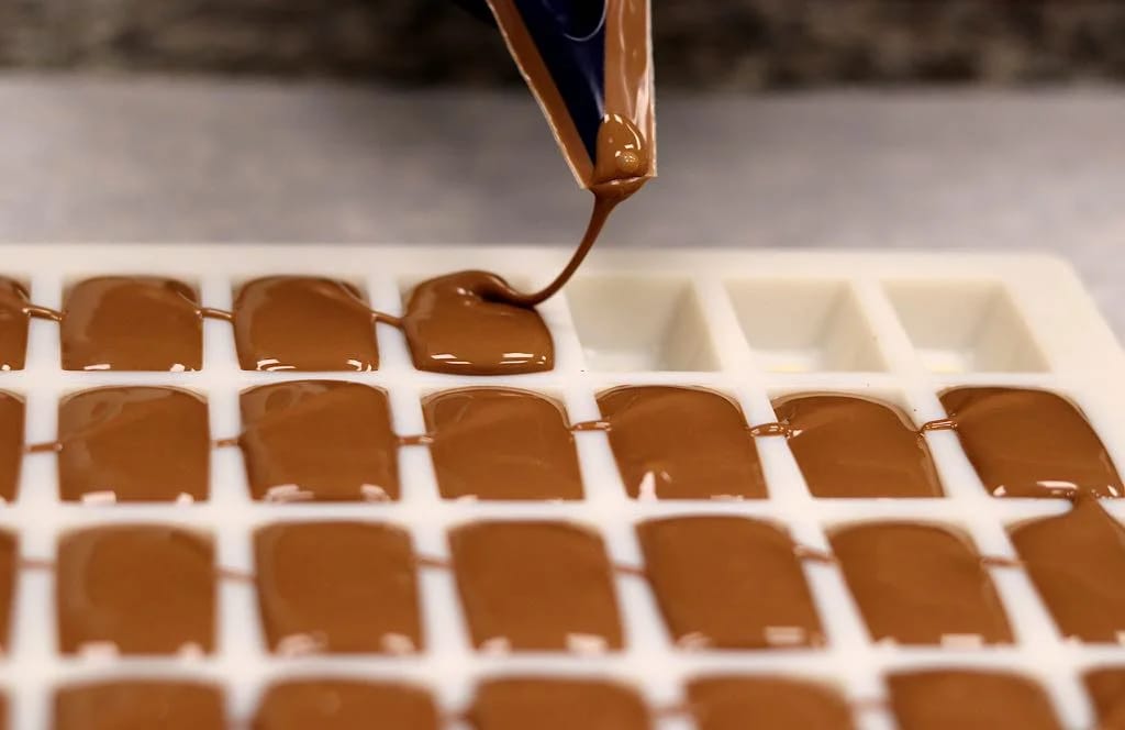 Pochage de chocolats à la main dans l'atelier Aux Délices Lorraines